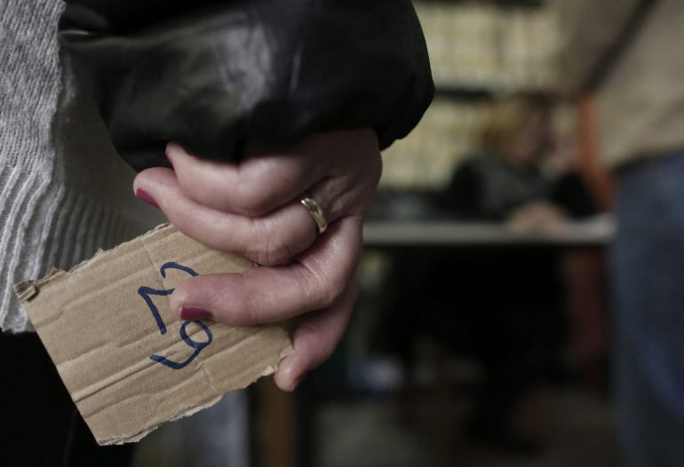 Una mujer espera para recibir una bolsa con comida en un banco de alimentos de Atenas Una mujer espera para recibir una bolsa con comida en un banco de alimentos de Atenas