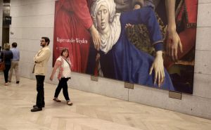 Dos espectadores junto a un cartel con un fragmento del "Descendimiento de la cruz" del flamenco Rogier van der Weyden, en el museo de El Prado. Dos espectadores junto a un cartel con un fragmento del "Descendimiento de la cruz" del flamenco Rogier van der Weyden, en el museo de El Prado.
