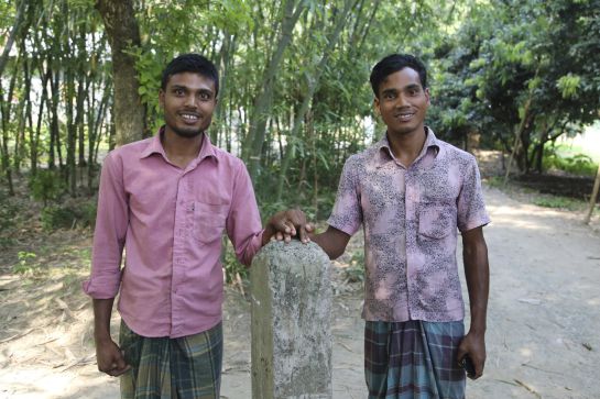 Dos habitantes del antiguo enclave indio en suelo bangladesí de Bashkata posan junto a un poste que marca el comienzo de soberanías de India y Bangladesh, ahora ya improcedente