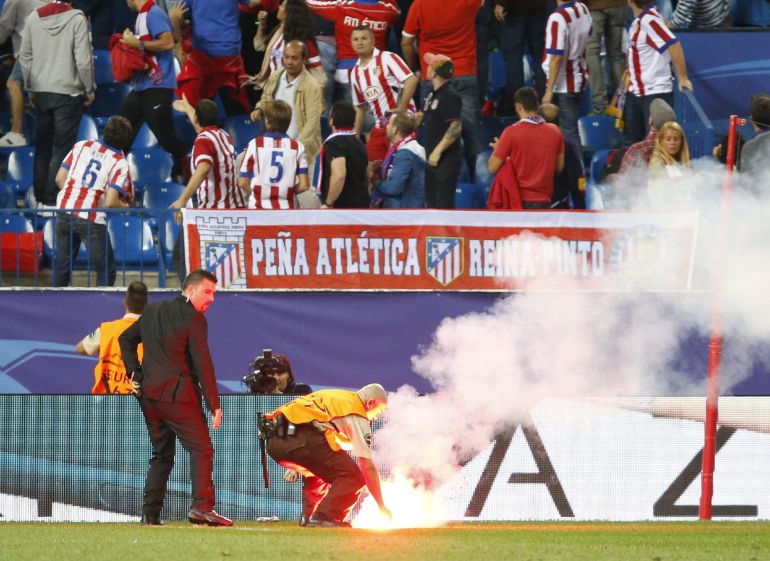 Operarios retiran una bengala del terreno de juego durante el partido de la Liga de Campeones entre Atlético de Madrid y Benfica Operarios retiran una bengala del terreno de juego durante el partido de la Liga de Campeones entre Atlético de Madrid y Benfica