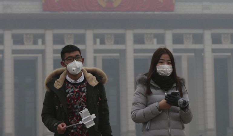 Una pareja usa mascarillas para protegerse de la contaminación ambiental durante una visita a la plaza de Tiananmen en Pekín (China). Una pareja usa mascarillas para protegerse de la contaminación ambiental durante una visita a la plaza de Tiananmen en Pekín (China).