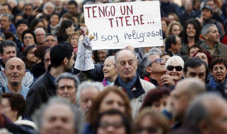 Una persona muestra un títere y un cartel alusivo durante la manifestación contra la corrupción en Valencia Una persona muestra un títere y un cartel alusivo durante la manifestación contra la corrupción en Valencia
