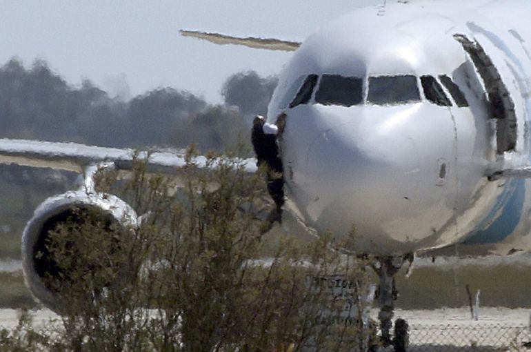 Un hombre se descuelga desde la ventanilla de la cabina del Airbus A320 de Egyptair obligado a aterrizar en el aeropuerto de Lárnaca. Un hombre se descuelga desde la ventanilla de la cabina del Airbus A320 de Egyptair obligado a aterrizar en el aeropuerto de Lárnaca.