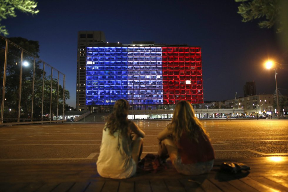 Dos jóvenes observan los colores de la bandera nacional francesa en un edificio del Tel Aviv, Israel. Dos jóvenes observan los colores de la bandera nacional francesa en un edificio del Tel Aviv, Israel.