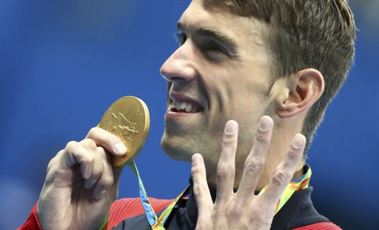 2016 Rio Olympics - Swimming - Victory Ceremony - Men's 200m Individual Medley Victory Ceremony - Olympic Aquatics Stadium - Rio de Janeiro, Brazil - 11/08/2016. Michael Phelps (USA) of USA poses with his gold medal. REUTERS/Michael Dalder FOR EDITORIAL USE ONLY. NOT FOR SALE FOR MARKETING OR ADVERTISING CAMPAIGNS. 2016 Rio Olympics - Swimming - Victory Ceremony - Men's 200m Individual Medley Victory Ceremony - Olympic Aquatics Stadium - Rio de Janeiro, Brazil - 11/08/2016. Michael Phelps (USA) of USA poses with his gold medal. REUTERS/Michael Dalder FOR EDITORIAL USE ONLY. NOT FOR SALE FOR MARKETING OR ADVERTISING CAMPAIGNS.