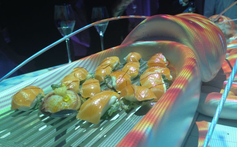 Falsos nigiris de salmón sobre queso, ocultos en la escultura de un bogavante sobre el que se proyectan luces de colores. Falsos nigiris de salmón sobre queso, ocultos en la escultura de un bogavante sobre el que se proyectan luces de colores.