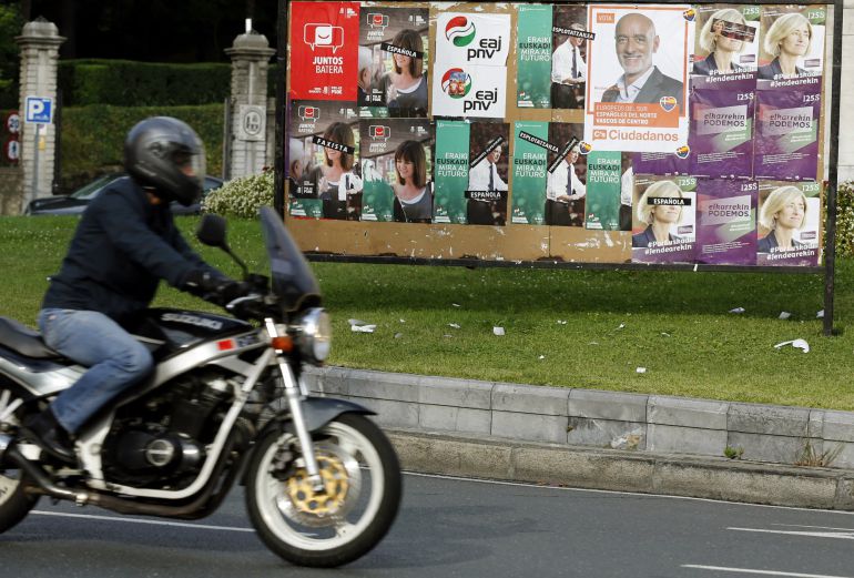 Un motorista pasa ante una valla con los candidatos a lehendakari en una calle de Bilbao Un motorista pasa ante una valla con los candidatos a lehendakari en una calle de Bilbao