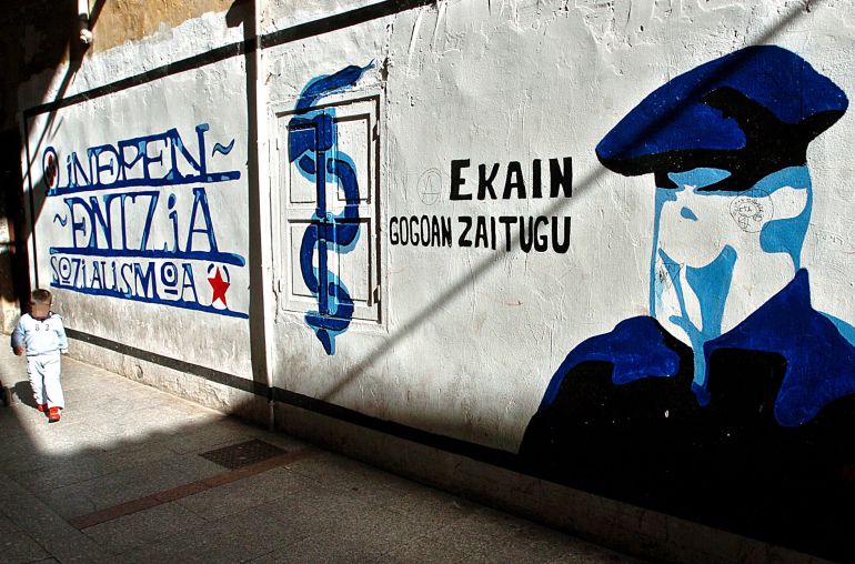 Un niño pasa junto a un mural que representa a un encapuchado junto al anagrama de ETA Un niño pasa junto a un mural que representa a un encapuchado junto al anagrama de ETA