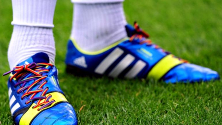 Un futbolista lleva atadas las botas con cordones con los colores del arcoiris Un futbolista lleva atadas las botas con cordones con los colores del arcoiris