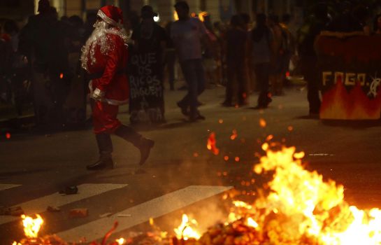 Un manifestante vestido como Santa Claus, junto a una barricada en Porto Alegre. Un manifestante vestido como Santa Claus, junto a una barricada en Porto Alegre.