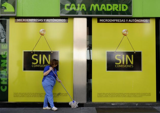 Una mujer limpia la entrada de una oficina de Bankia en Sevilla Una mujer limpia la entrada de una oficina de Bankia en Sevilla