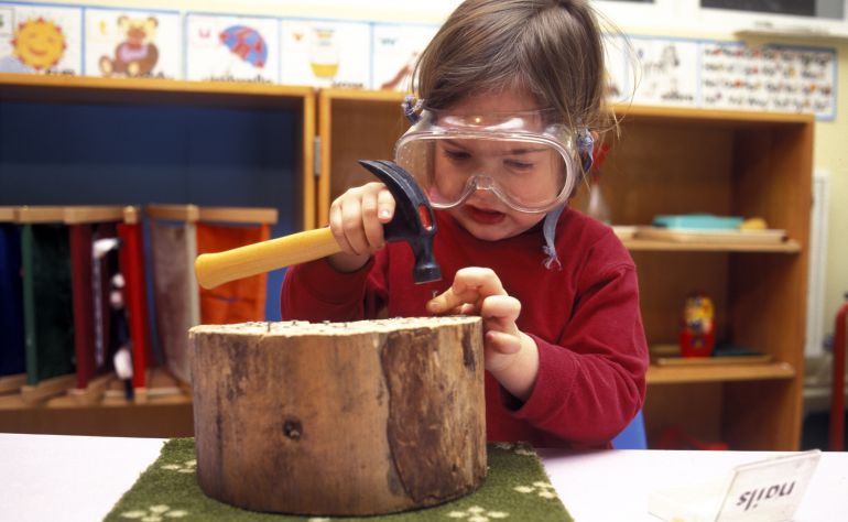 Una niña trabaja con la madera en una escuela Montessori. Una niña trabaja con la madera en una escuela Montessori.