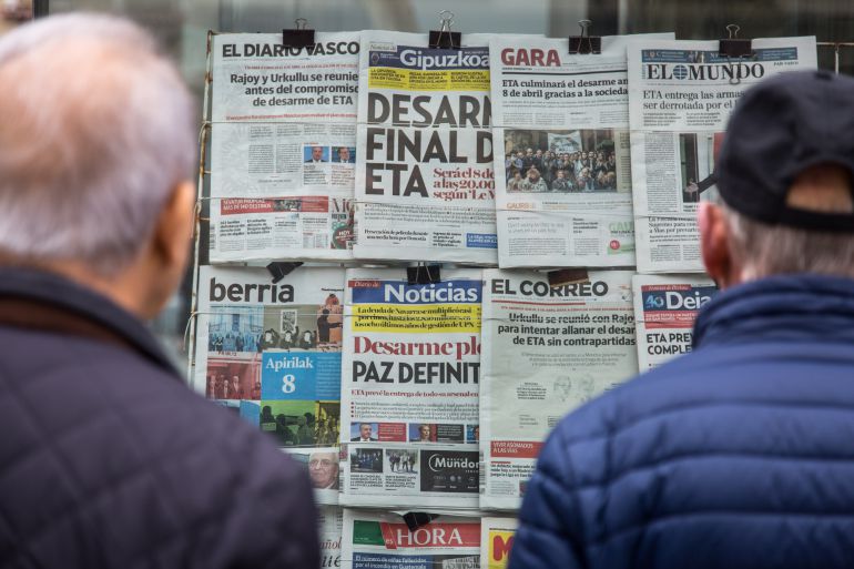 Dos hombres ante un puesto de prensa con la noticia del desarme de ETA en la portada de los periódicos Dos hombres ante un puesto de prensa con la noticia del desarme de ETA en la portada de los periódicos