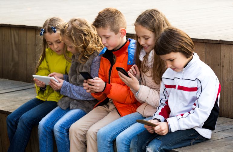 Un grupo de chicos utiliza tabletas y teléfonos móviles. Un grupo de chicos utiliza tabletas y teléfonos móviles.