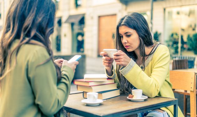 Dos chicas consultan su teléfono móvil. Dos chicas consultan su teléfono móvil.