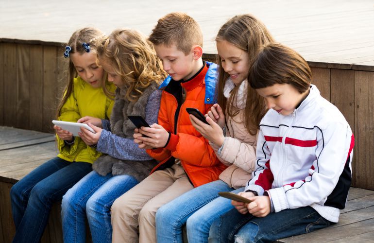 Un grupo de chicos utiliza tabletas y teléfonos móviles. Un grupo de chicos utiliza tabletas y teléfonos móviles.