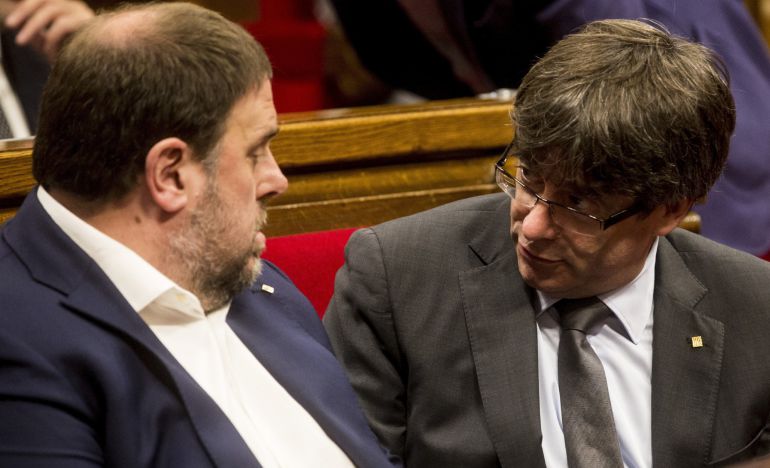 El presidente de la Generalitat, Carles Puigdemont, junto al vicepresidente Oriol Junqueras (i), durante el pleno del parlamento de Cataluña, el día después de aprobarse la reforma del reglamento de la cámara catalana El presidente de la Generalitat, Carles Puigdemont, junto al vicepresidente Oriol Junqueras (i), durante el pleno del parlamento de Cataluña, el día después de aprobarse la reforma del reglamento de la cámara catalana