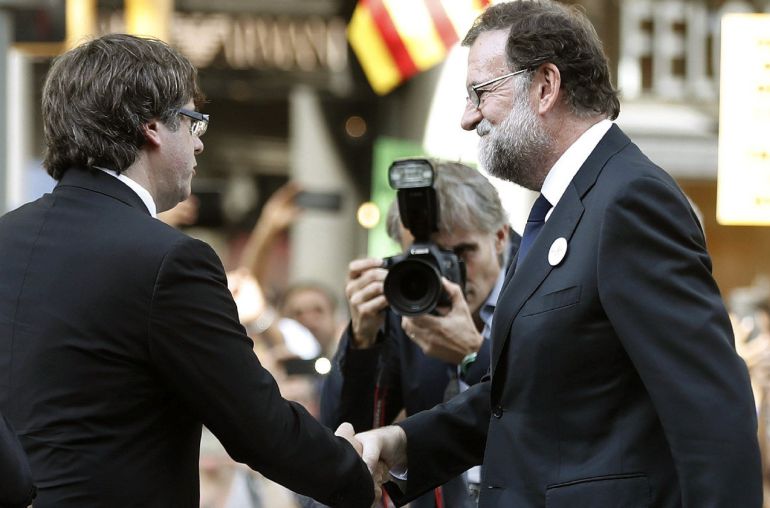 El presidente del Gobierno Mariano Rajoy (d) saluda al presidente catalán Carles Puigdemont (c) durante la manifestación contra los atentados yihadistas en Cataluña. El presidente del Gobierno Mariano Rajoy (d) saluda al presidente catalán Carles Puigdemont (c) durante la manifestación contra los atentados yihadistas en Cataluña.