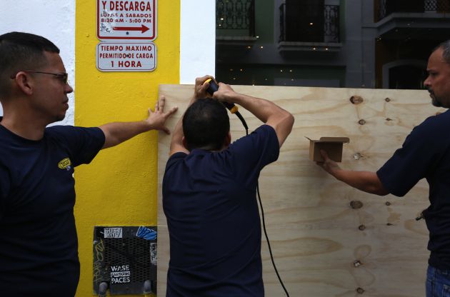 Unos hombres cubren la entrada de un local con tablas de madera este martes en San Juan (Puerto Rico) Unos hombres cubren la entrada de un local con tablas de madera este martes en San Juan (Puerto Rico)