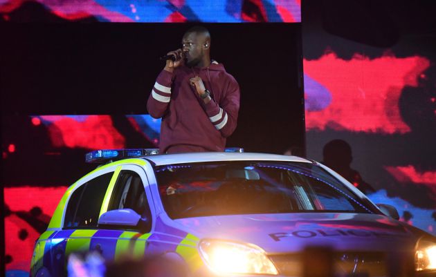 El rapero Stormzy, a bordo de un coche de policía sobre el escenario. El rapero Stormzy, a bordo de un coche de policía sobre el escenario.