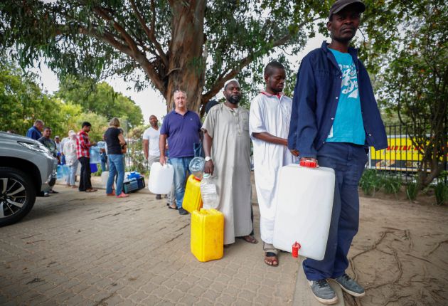 Varias personas hacen cola para llenar garrafas de agua procedente de un arroyo en un punto de recogida en Ciudad del Cabo (Sudáfrica). Varias personas hacen cola para llenar garrafas de agua procedente de un arroyo en un punto de recogida en Ciudad del Cabo (Sudáfrica).