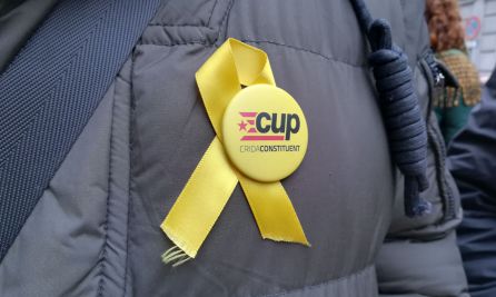 Un hombre con una chapa de la CUP y un lazo amarillo en el abrigo Un hombre con una chapa de la CUP y un lazo amarillo en el abrigo