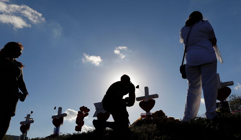 Un hombre reza frente a una cruz durante el homenaje a las víctimas del tiroteo. Un hombre reza frente a una cruz durante el homenaje a las víctimas del tiroteo.
