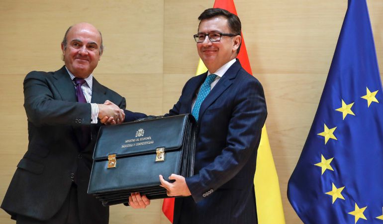 El ministro de Economía, Industria y Competitividad, Román Escolano (d), toma posesión de su cargo en un acto en el que su antecesor, Luis de Guindos (i), le traspasa la cartera del departamento. El ministro de Economía, Industria y Competitividad, Román Escolano (d), toma posesión de su cargo en un acto en el que su antecesor, Luis de Guindos (i), le traspasa la cartera del departamento.