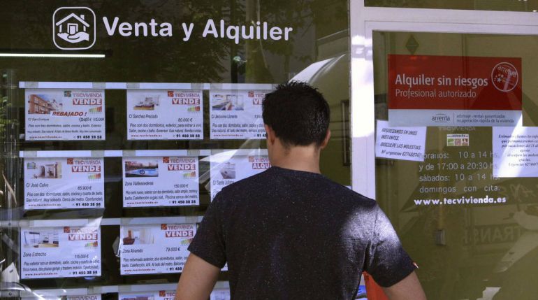 Un hombre mira anuncios de venta y alquiler de vivienda en una inmobiliaria Un hombre mira anuncios de venta y alquiler de vivienda en una inmobiliaria