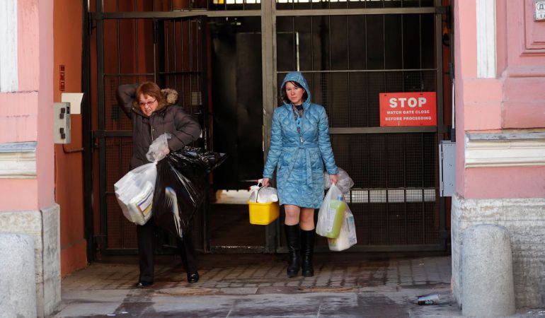 Dos mujeres cargan con varias bolsas mientras salen del Consulado General de EE. UU. en San Petersburgo (Rusia). Dos mujeres cargan con varias bolsas mientras salen del Consulado General de EE. UU. en San Petersburgo (Rusia).