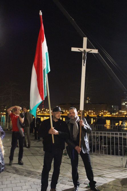 Dos partidarios de Orban con una bandera húngara y un crucifijo Dos partidarios de Orban con una bandera húngara y un crucifijo