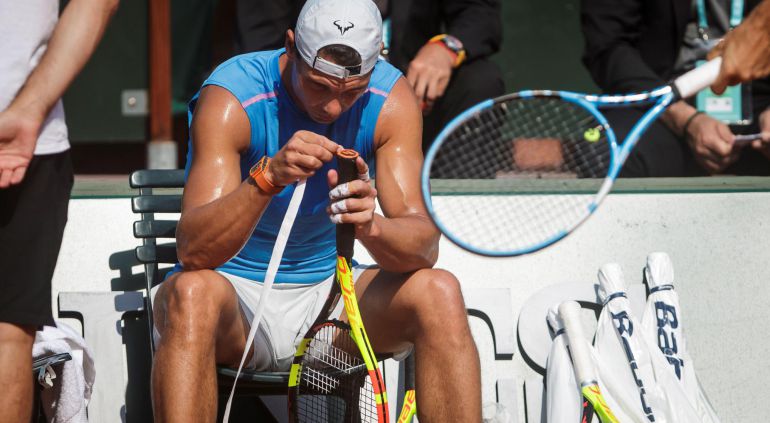 Rafael Nadal se afana en cambiar el puño de su raqueta durante un entrenamiento Rafael Nadal se afana en cambiar el puño de su raqueta durante un entrenamiento