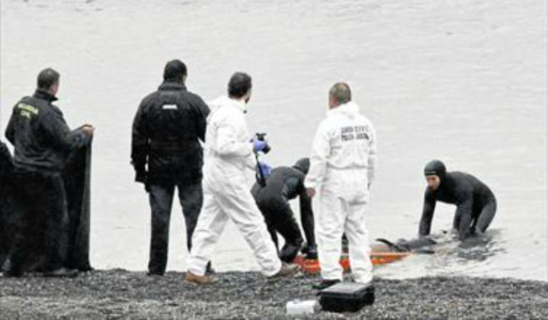 Agentes de la Guardia Civil recogen uno de los cadáveres aparecidos en la playa del Tarajal. Agentes de la Guardia Civil recogen uno de los cadáveres aparecidos en la playa del Tarajal.