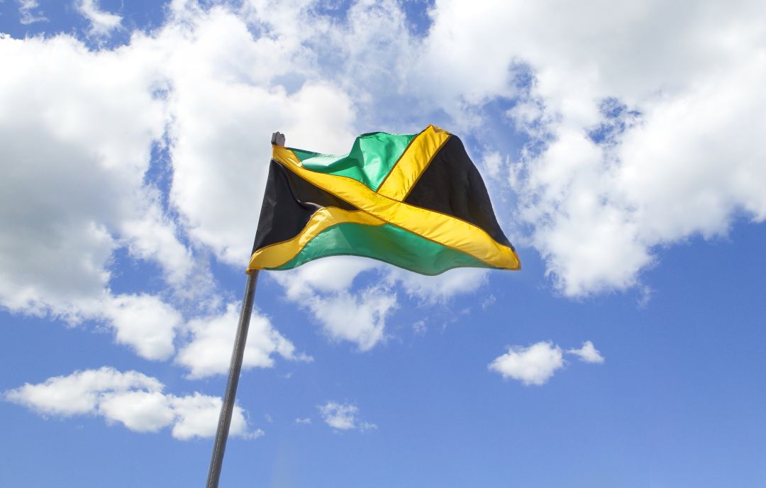 Bandera jamaicana ondeando en un edificio de Kingston Bandera jamaicana ondeando en un edificio de Kingston