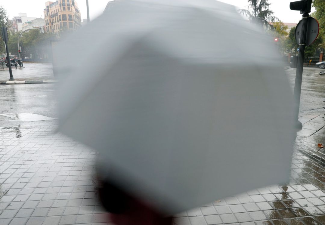 Una persona se cubre de la lluvia hoy en Madrid Una persona se cubre de la lluvia hoy en Madrid
