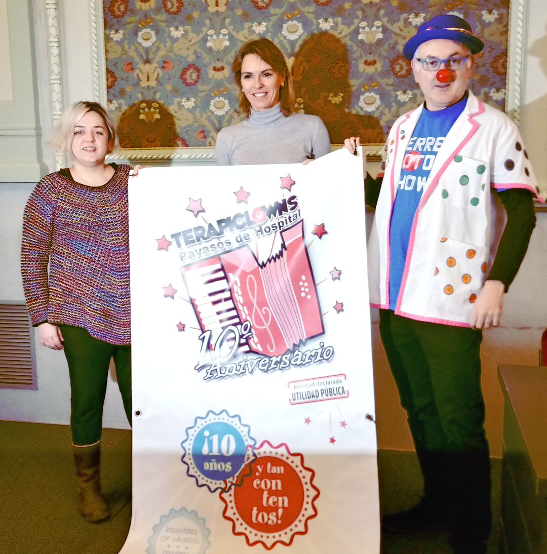 Alicia y Carlos (Terapiclowns) flanqueando a la concejala de cultura, Lorena de la Fuente, con el cartel del 10 aniversario de la asociación Alicia y Carlos (Terapiclowns) flanqueando a la concejala de cultura, Lorena de la Fuente, con el cartel del 10 aniversario de la asociación