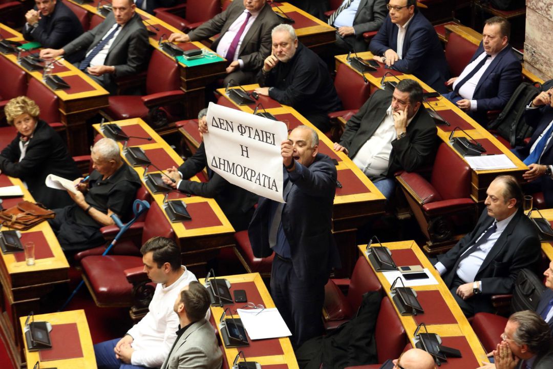 John Saridis, integrante del partido Unión de Centristas, sostiene un cartel en el que puede leerse ''No culpen a la Democracia'' John Saridis, integrante del partido Unión de Centristas, sostiene un cartel en el que puede leerse ''No culpen a la Democracia''