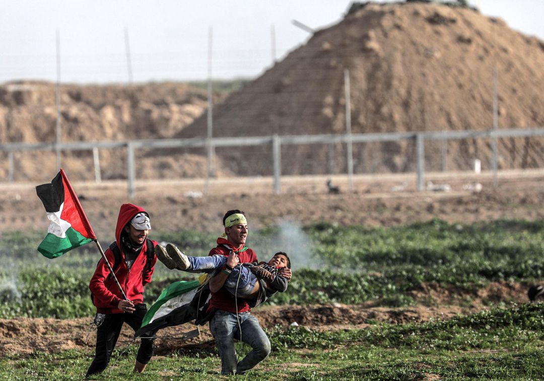 Dos jóvenes palestinos llevan en brazos a un niño herido durante las protestas de los viernes contra Israel en la ciudad cisjordana de Gaza. Dos jóvenes palestinos llevan en brazos a un niño herido durante las protestas de los viernes contra Israel en la ciudad cisjordana de Gaza.