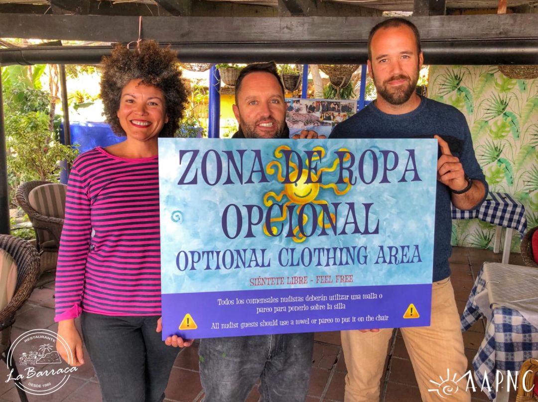 El presidente de la Asociación, Jesús Segura, la vicepresidenta, Ager Toro y el propietario del restaurante La Barraca, Isaac Rodriguezs muestran el cartel de "Zona de ropa opcional" El presidente de la Asociación, Jesús Segura, la vicepresidenta, Ager Toro y el propietario del restaurante La Barraca, Isaac Rodriguezs muestran el cartel de "Zona de ropa opcional"