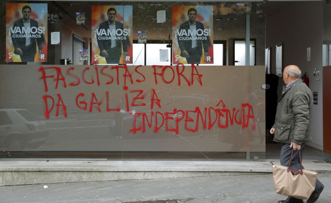 Una persona pasa delante de la sede del partido Ciudadanos, que ha aparecido rota y con la pintada "Fuera fascistas de Galicia. Independencia", esta mañana en Santiago de Compostela. Una persona pasa delante de la sede del partido Ciudadanos, que ha aparecido rota y con la pintada "Fuera fascistas de Galicia. Independencia", esta mañana en Santiago de Compostela.