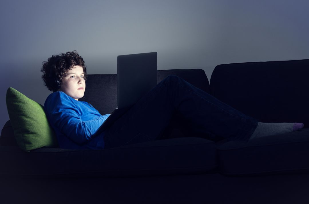 Un adolescente mirando el ordenador en el sofa. Un adolescente mirando el ordenador en el sofa.