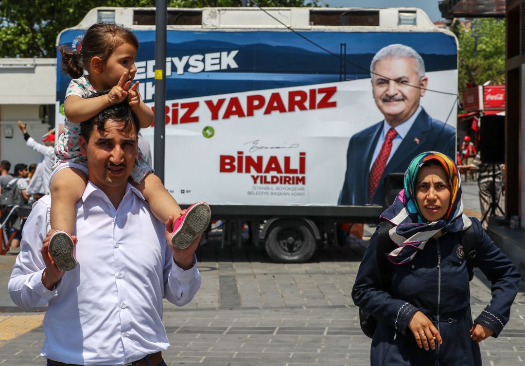 Una pareja con su hija pasan frente a una oficina electoral móvil en la que aparece Binali Yildirim, candidato a la alcaldía de Estambul por el partido gobernante en Turquía, el Partido de la Justicia y el Desarrollo (AKP). Una pareja con su hija pasan frente a una oficina electoral móvil en la que aparece Binali Yildirim, candidato a la alcaldía de Estambul por el partido gobernante en Turquía, el Partido de la Justicia y el Desarrollo (AKP).