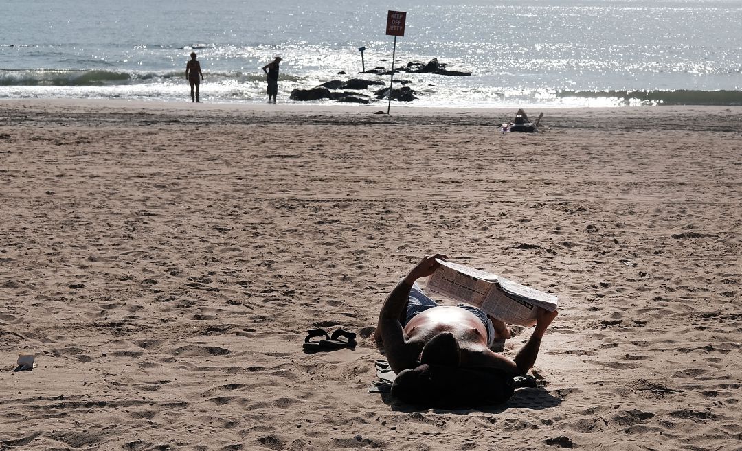 Un lector aprovecha la tranquilidad de una playa para leer un periódico. Un lector aprovecha la tranquilidad de una playa para leer un periódico.