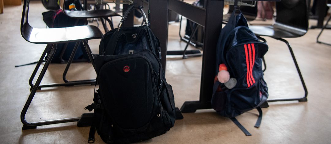 Mochilas colgadas en los pupitres de una clase Mochilas colgadas en los pupitres de una clase