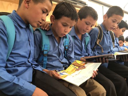Un grupo de niños leen libros en el autobús-biblioteca Un grupo de niños leen libros en el autobús-biblioteca