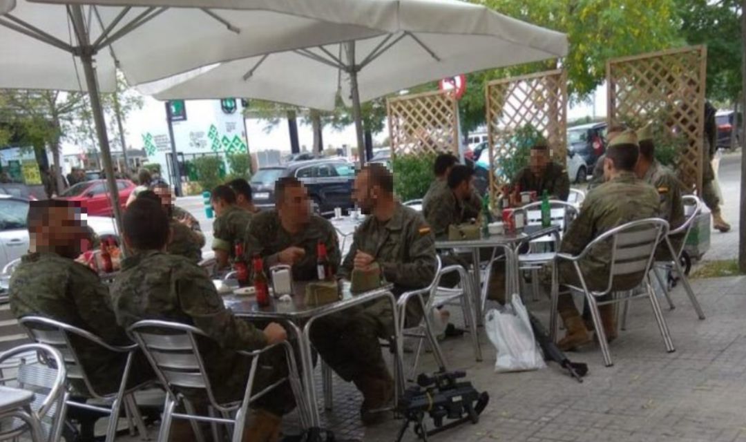 Un grupo de militares sentados en una terraza con armas largas en el suelo. Un grupo de militares sentados en una terraza con armas largas en el suelo.