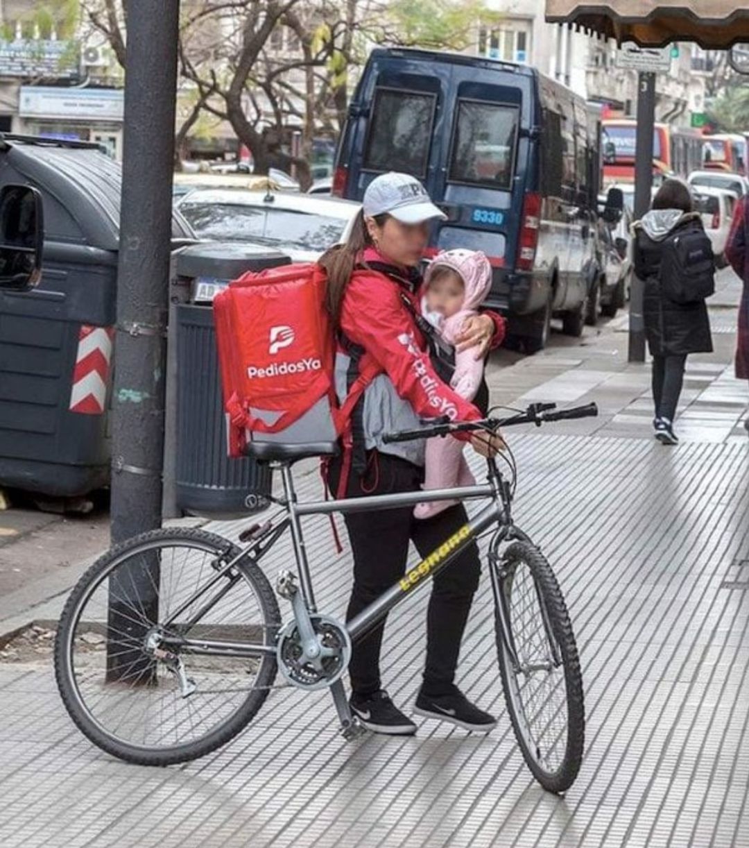 La repartidora con su hijo sobre su pecho fotografiada en Buenos Aires, Argentina. La repartidora con su hijo sobre su pecho fotografiada en Buenos Aires, Argentina.