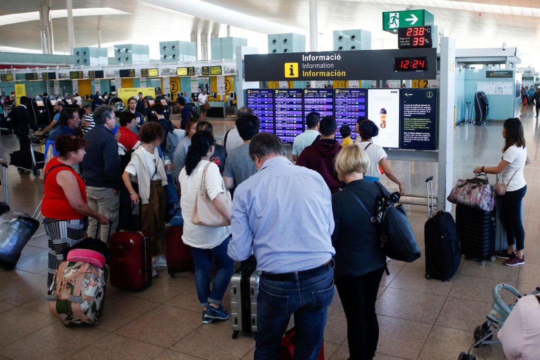 Varios viajeros observan horarios de vuelo en el Aeropuerto de Barcelona Varios viajeros observan horarios de vuelo en el Aeropuerto de Barcelona