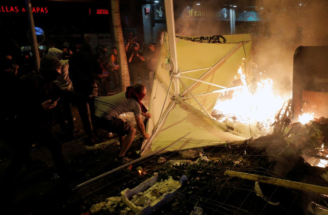 Un radical arroja una sombrilla a una hoguera callejera para reavivarla. Un radical arroja una sombrilla a una hoguera callejera para reavivarla.