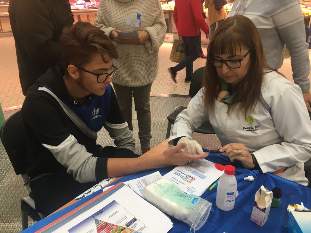 Una enfermera realiza el test de glucemia a un joven Una enfermera realiza el test de glucemia a un joven
